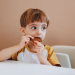 Adorable young boy in a casual setting enjoying a delicious cookie.